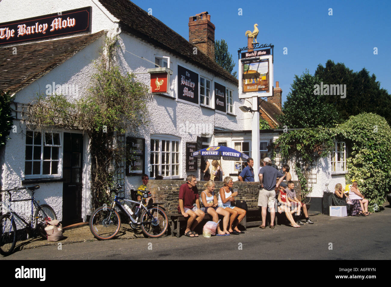 Le pub du village de campagne de truies d'orge avec des clients assis dehors pendant la chaude journée ensoleillée d'été en profitant du soleil. Tilford Surrey Angleterre Royaume-Uni Grande-Bretagne Banque D'Images
