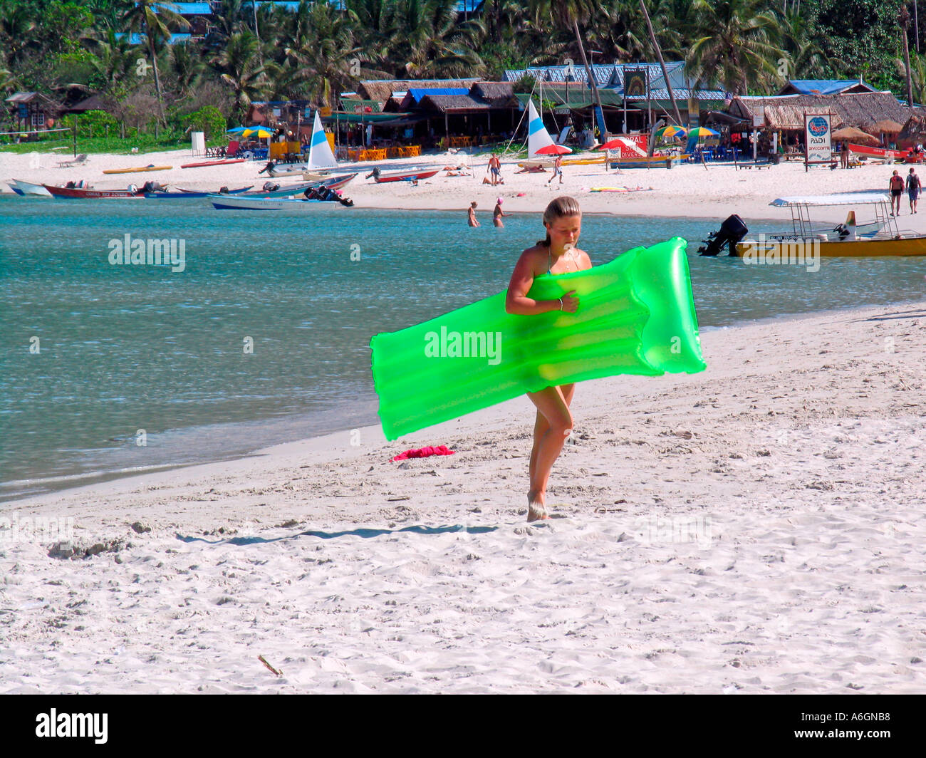 Jeune femme marche sur plage avec matelas d'air vert Perhentian Kecil Malaisie Banque D'Images