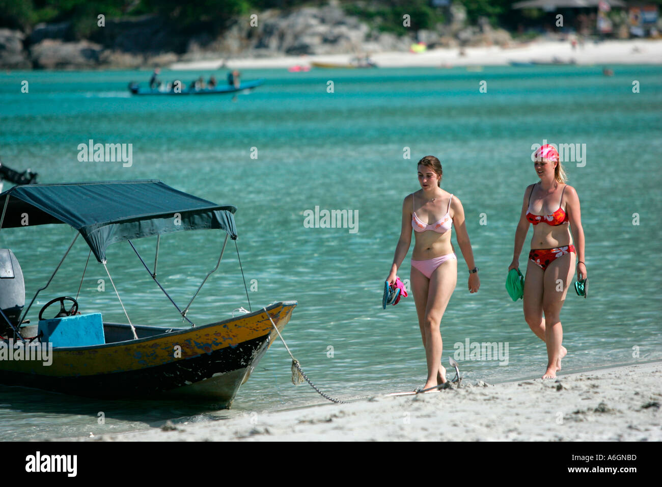 Deux jeunes femmes en bikini à pied bateau ancré passé Perhentian Kecil Malaisie Long Beach Banque D'Images