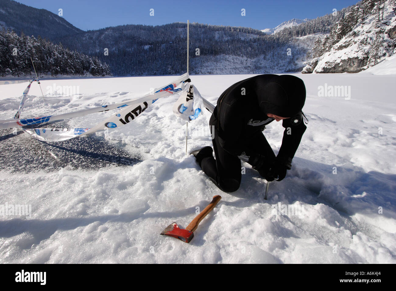Scuba Diver fixe vis à glace sur un lac gelé Banque D'Images