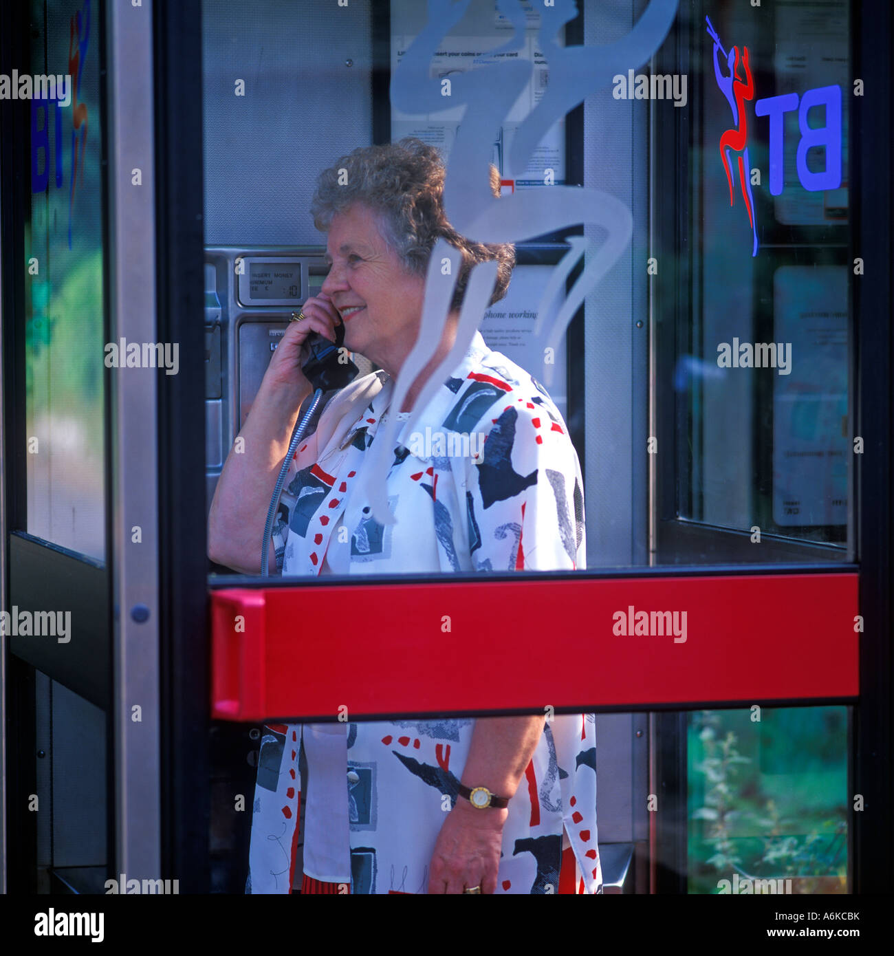 Femme PARLANT DANS UNE PHONEBOX BT Banque D'Images