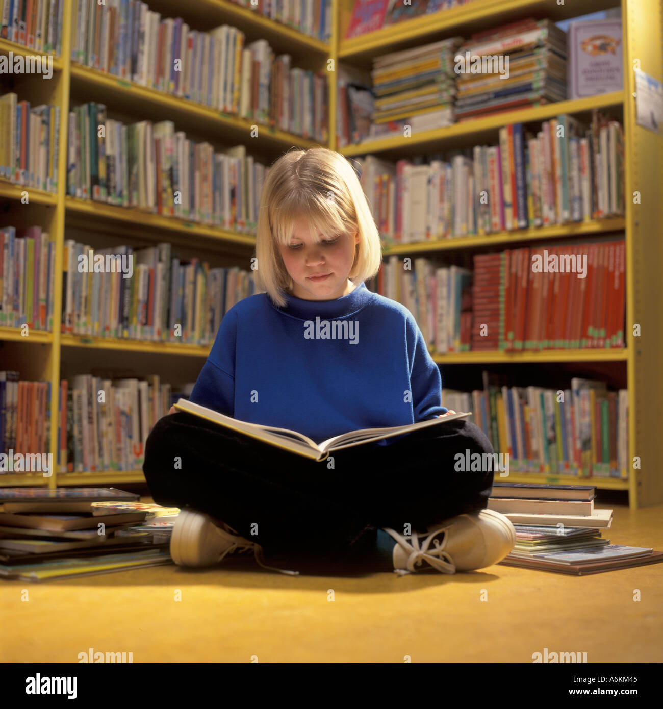 Jeune fille lisant un livre dans la bibliothèque Banque D'Images