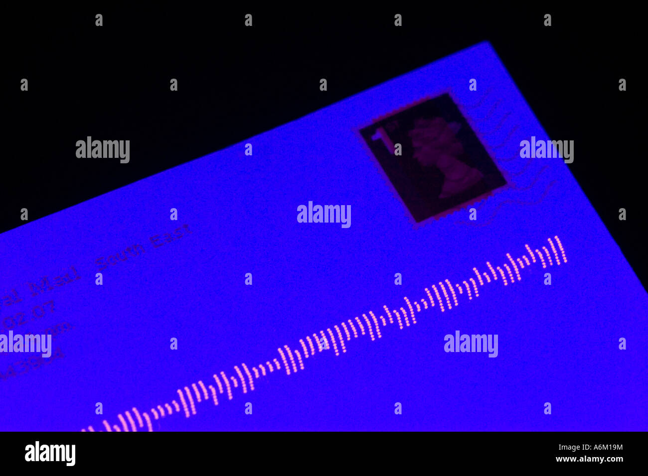 Une lettre illuminé par la lumière ultraviolette montrant le code à barres lisible par machine fluorescent Banque D'Images