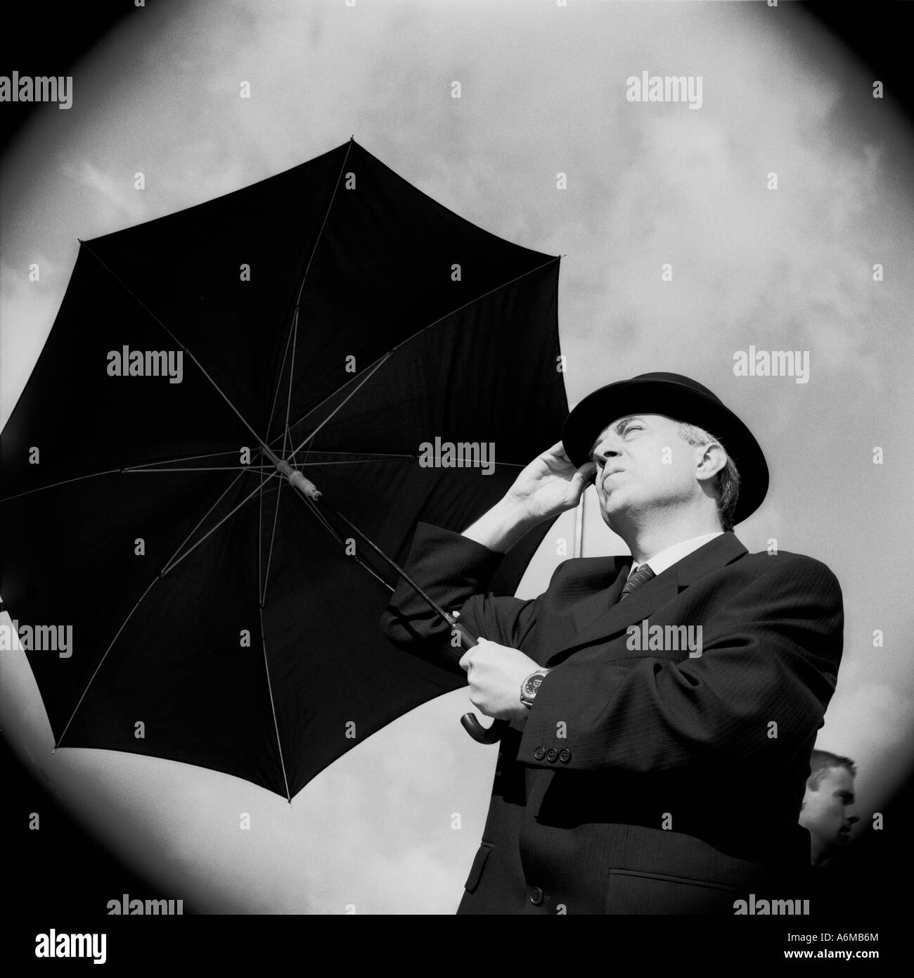 City gent en chapeau de style bowling avec parapluie donnant sur le ciel Banque D'Images