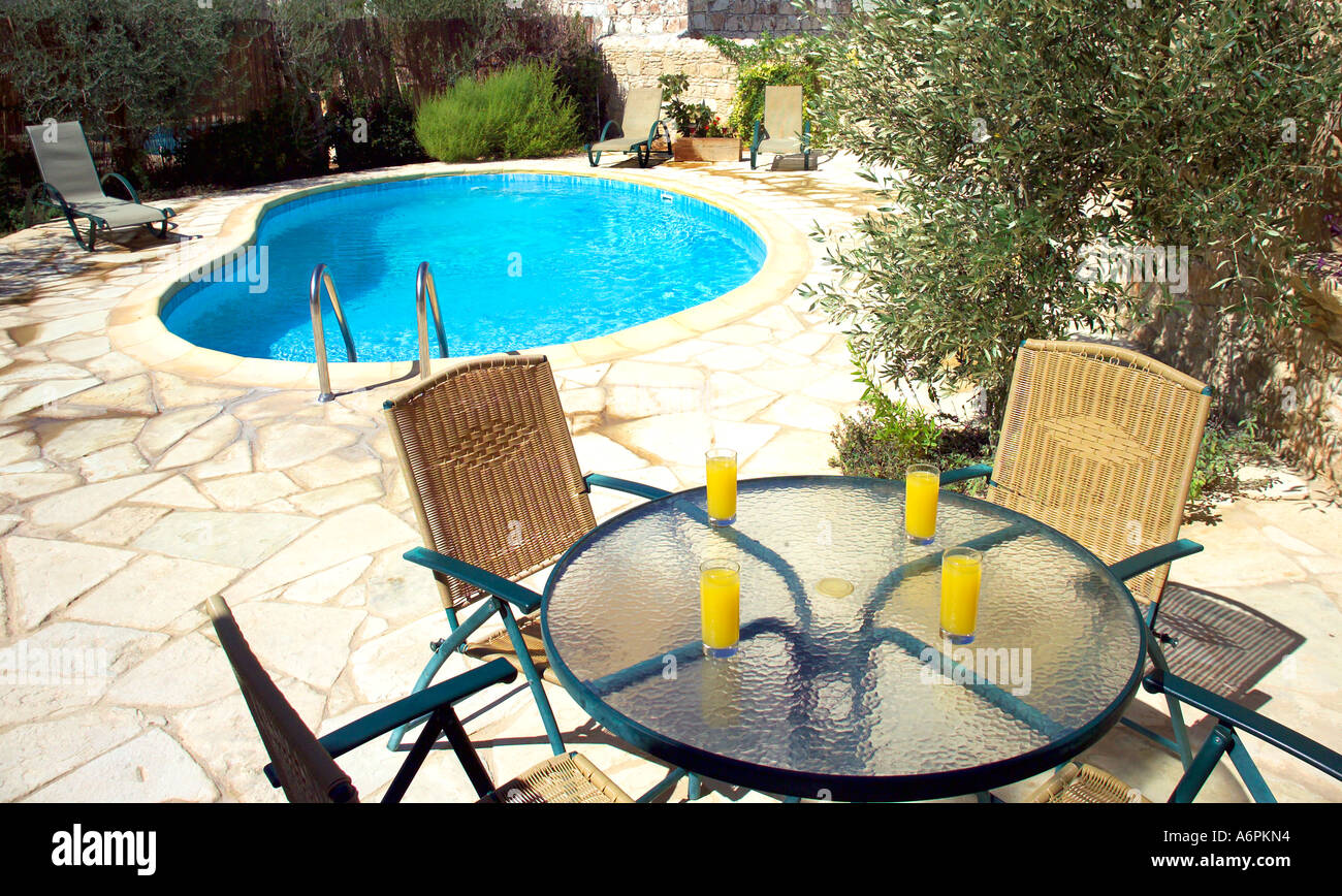 Réglage de la table avec du jus d'ORANGE EN PLEIN AIR AU SOLEIL AVEC PISCINE EN ARRIÈRE-PLAN Banque D'Images