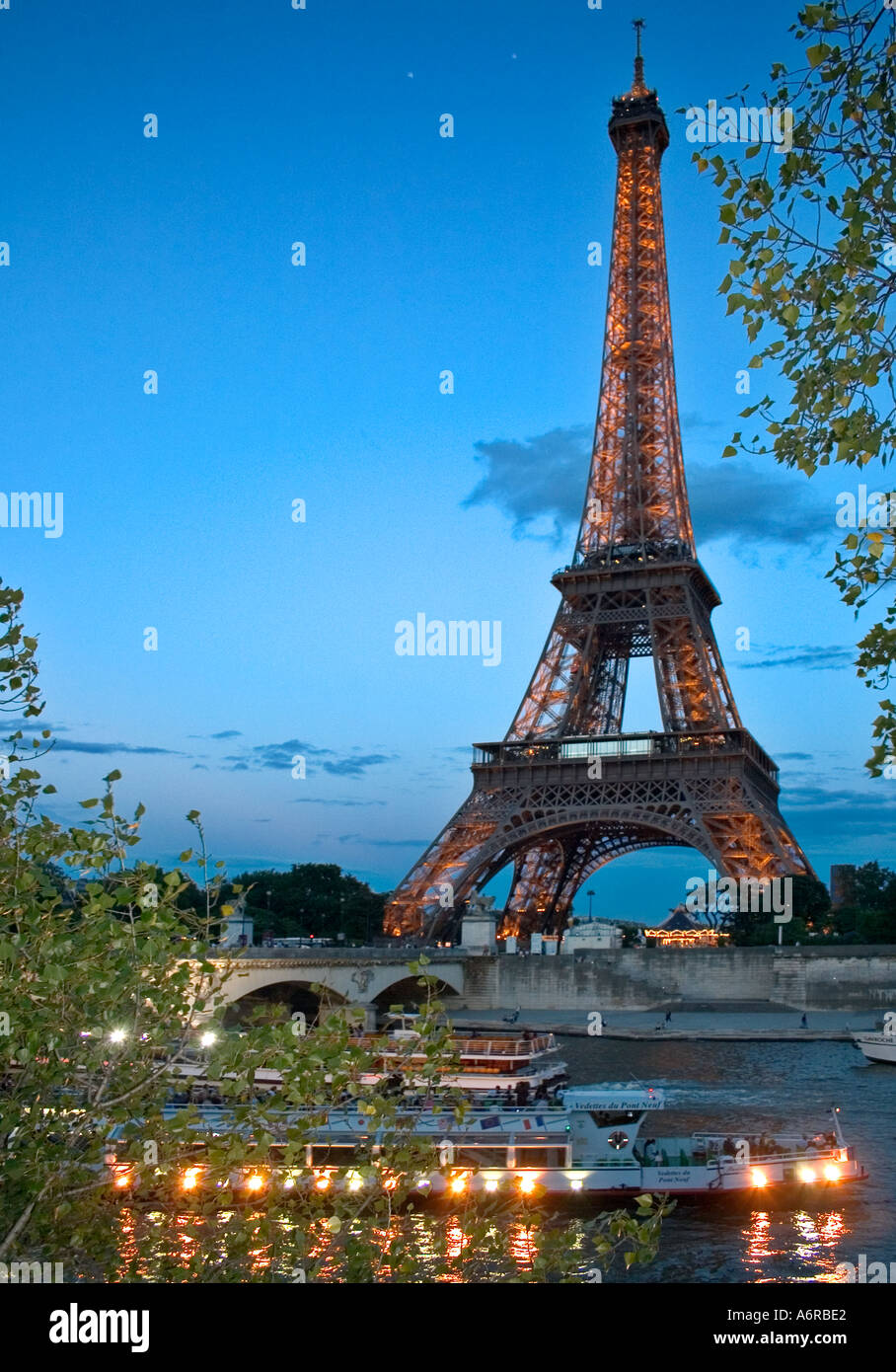 Tour Eiffel bateaux touristiques crépuscule avec des lumières en passant par en Seine en premier plan Paris France Banque D'Images