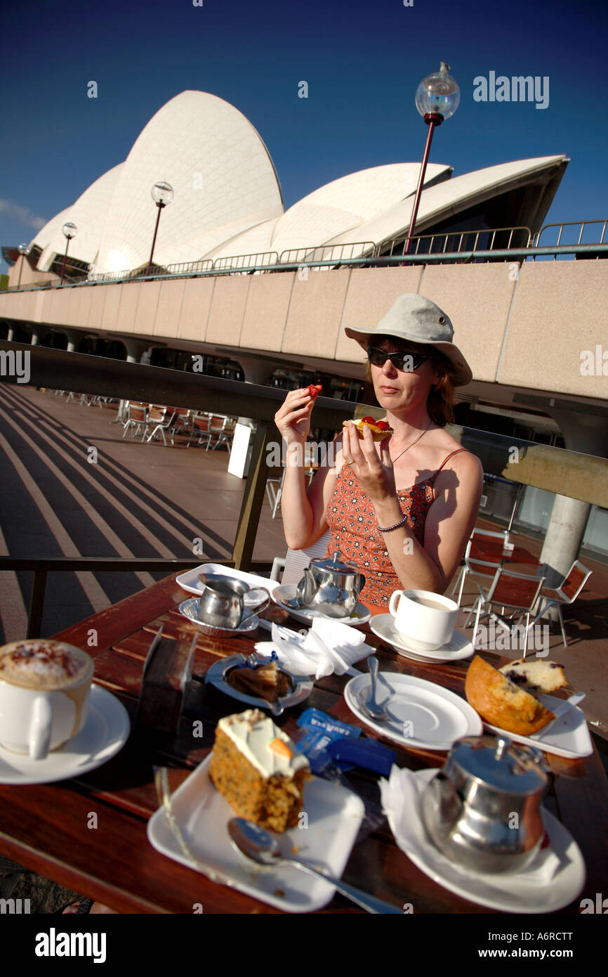 Une femme manger un gâteau à l'extérieur de l'Opéra de Sydney. Banque D'Images