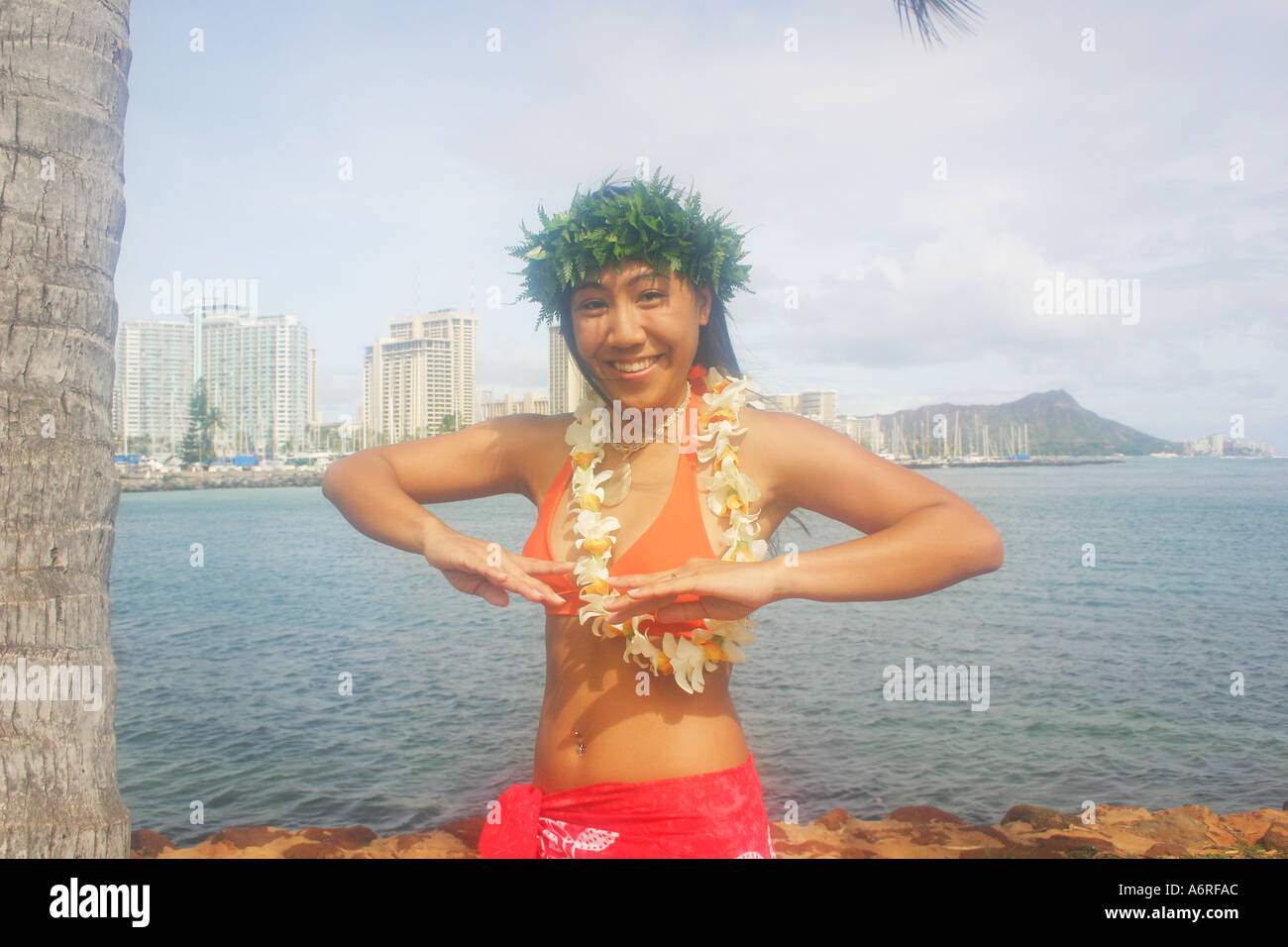 Jeune femme hawaïenne locales effectuant la danse hula avec lei avec Diamond Head Crater et Waikiki en arrière-plan Banque D'Images