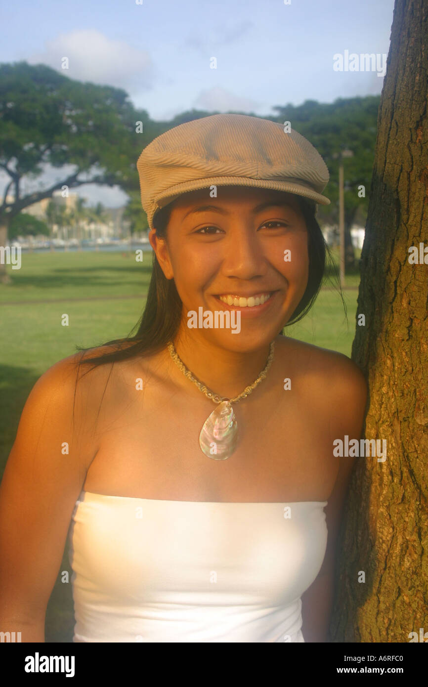 Jeune femme hawaïenne dans des vêtements décontractés et chapeau et collier smiling Banque D'Images