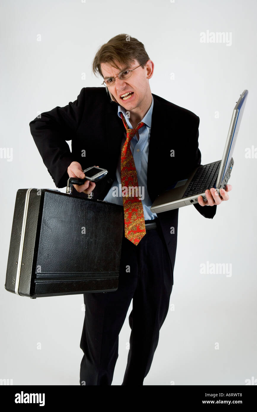 L'HOMME D'AFFAIRES EN COSTUME SOMBRE À SOULIGNÉ PARLANT AU TÉLÉPHONE ET ESSAIE DE CONTENIR UN ORDINATEUR PORTABLE PORTE-DOCUMENTS ET organiseur personnel Banque D'Images