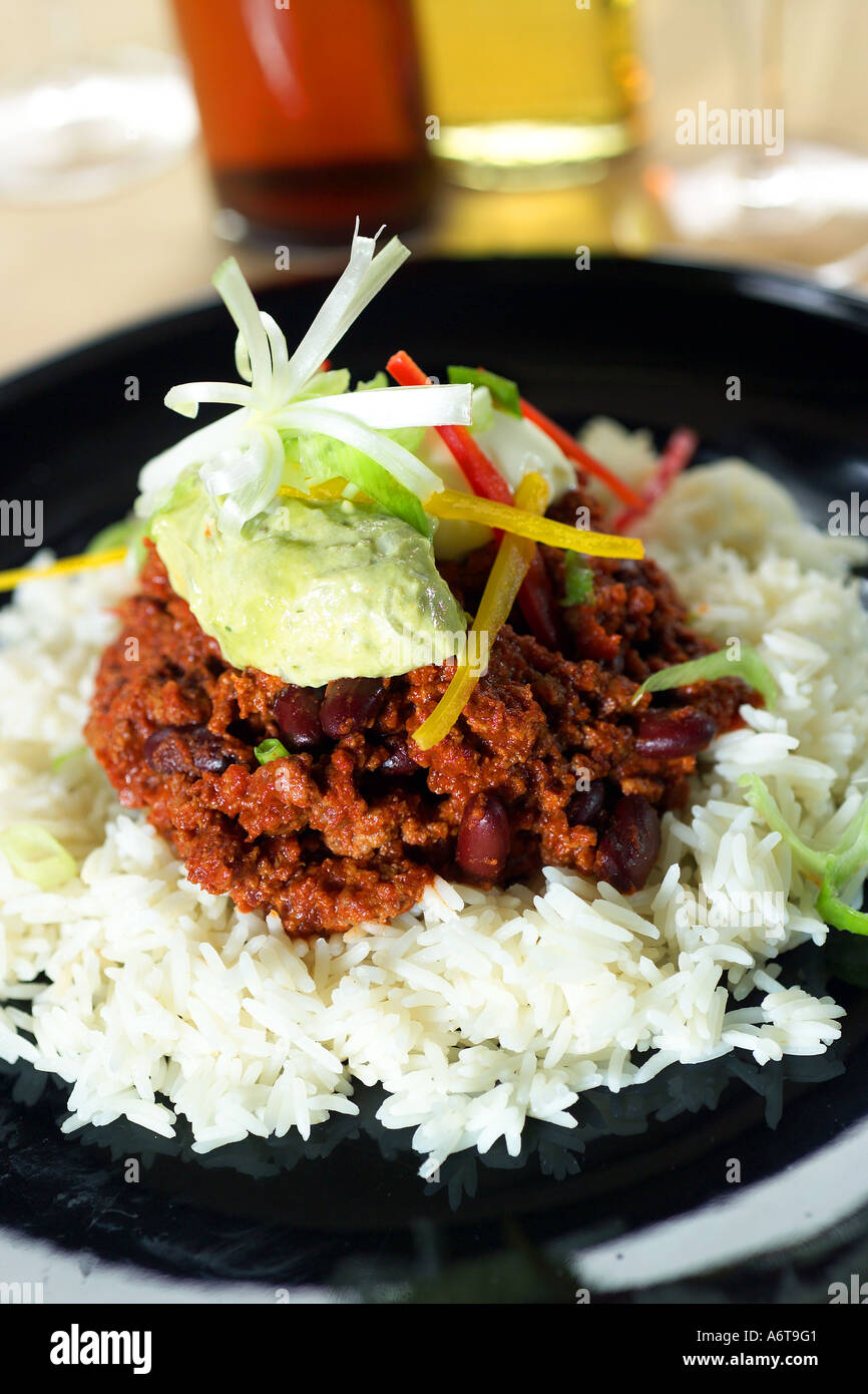 Mexican Chili con carne servi avec riz basmati blanc sur une plaque noire avec jaune rouge et verte salade Banque D'Images