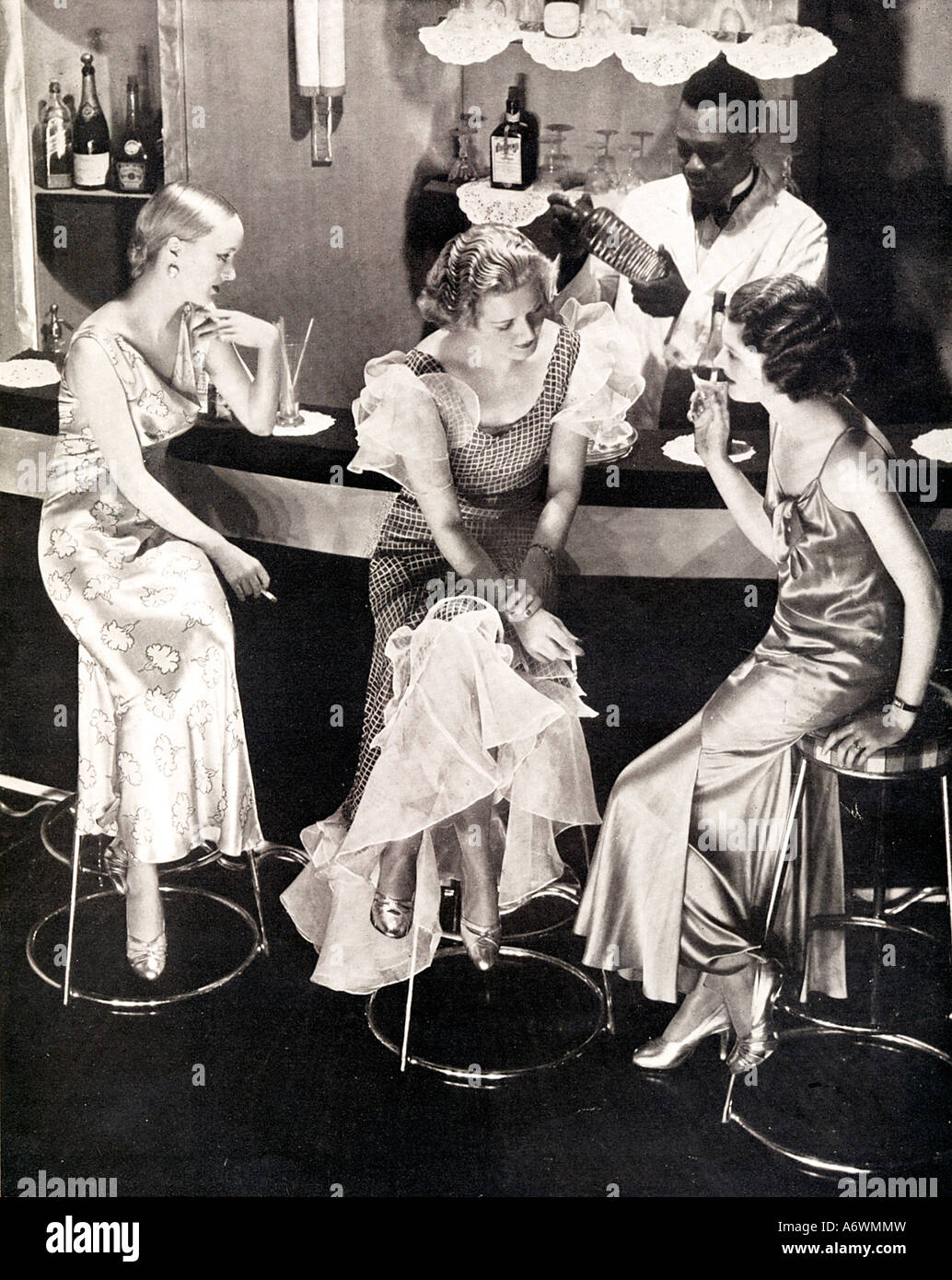 Bar à cocktails 1934 photo de mode de trois grosse bébête soirée mesdames en attente à la barre pour leurs boissons Banque D'Images