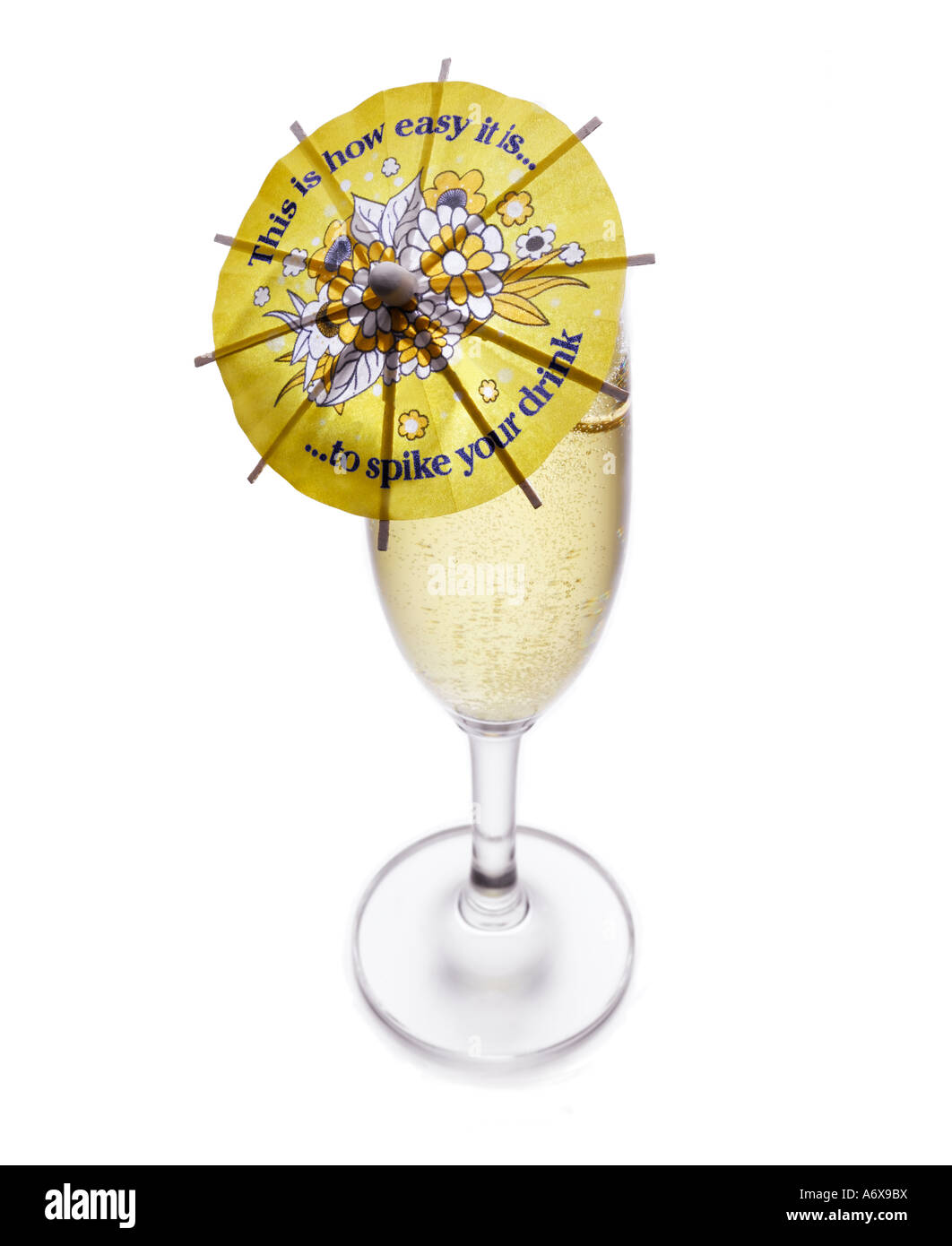 Un cocktail parapluie dans un verre de Champagne montrant comment il est facile de placer quelque chose dans votre verre verre dopé. Banque D'Images