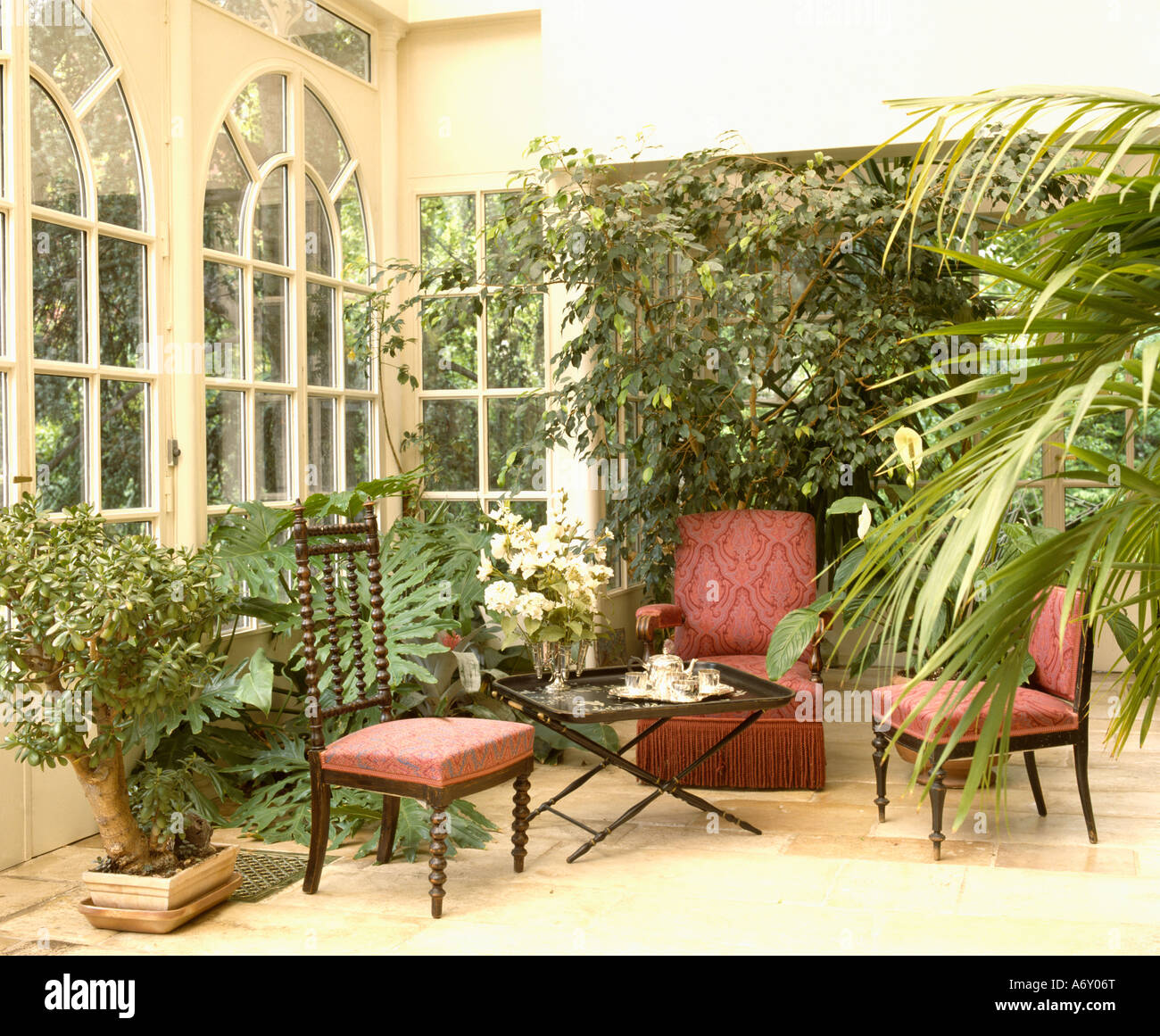 Chaises avec tissus rouges dans la véranda extension avec des plantes d'intérieur Banque D'Images