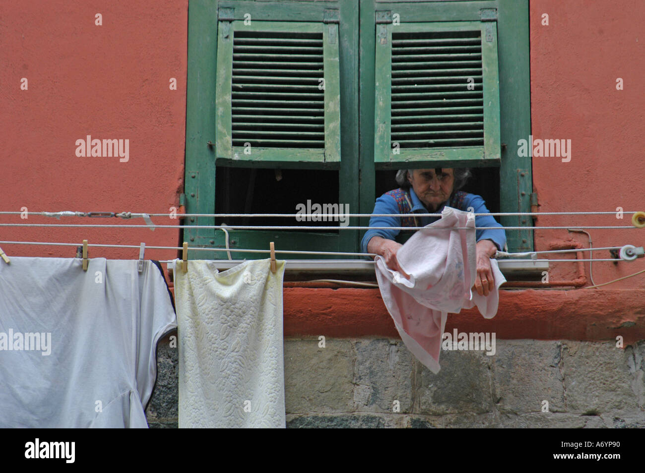 Vieille Femme italienne étendre le linge d'une fenêtre à Vernazza, Cinque Terre Banque D'Images