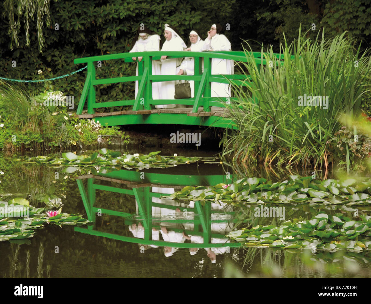 Quatre moniales debout sur le pont japonais dans le jardin de la peintre impressionniste Claude Monet GIVERNY Eure Normandie Fran Banque D'Images