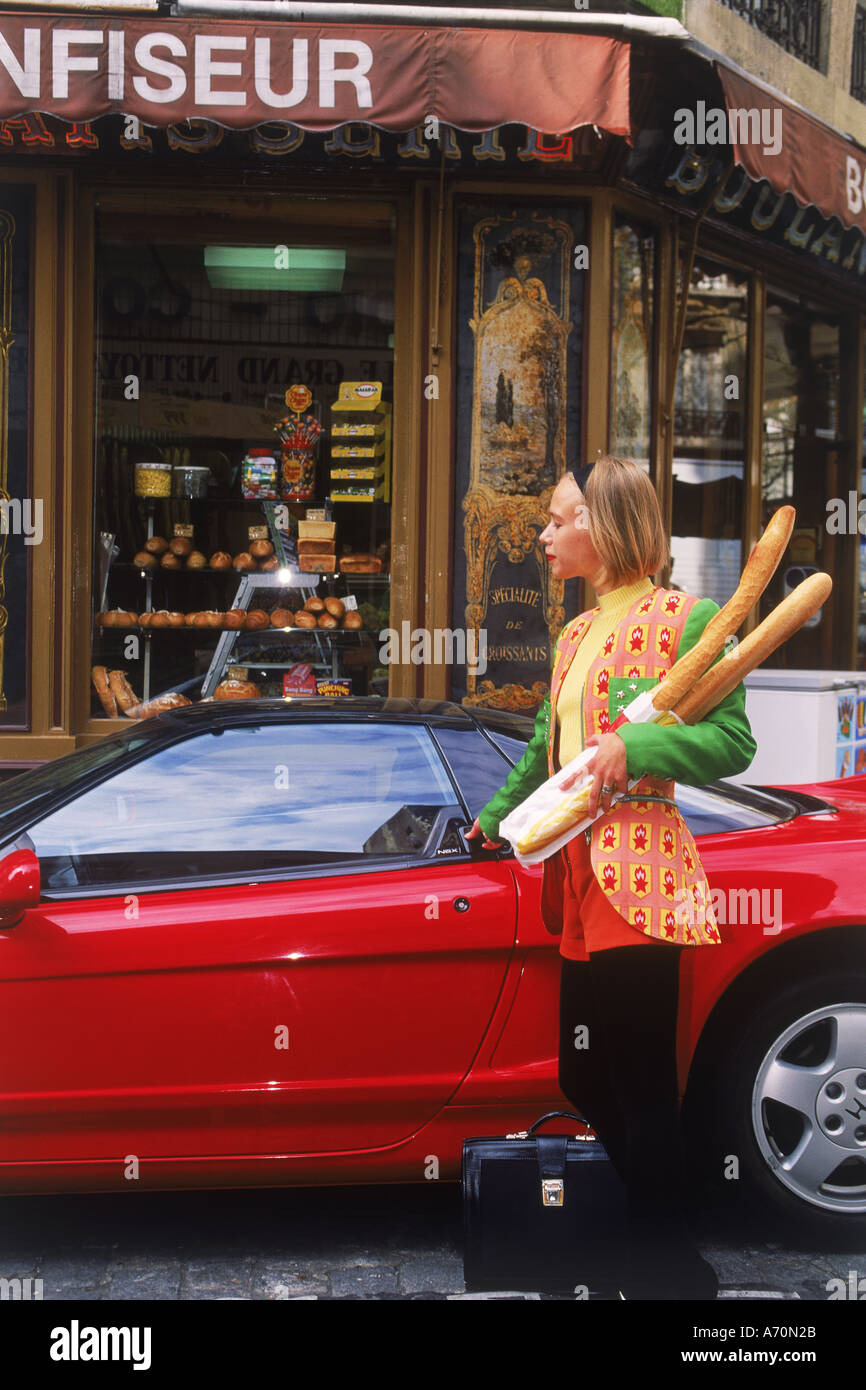 Femme française avec porte-documents et des baguettes d'entrer cher voiture de sport à l'extérieur de boulangerie ou boulangeria à Paris Banque D'Images