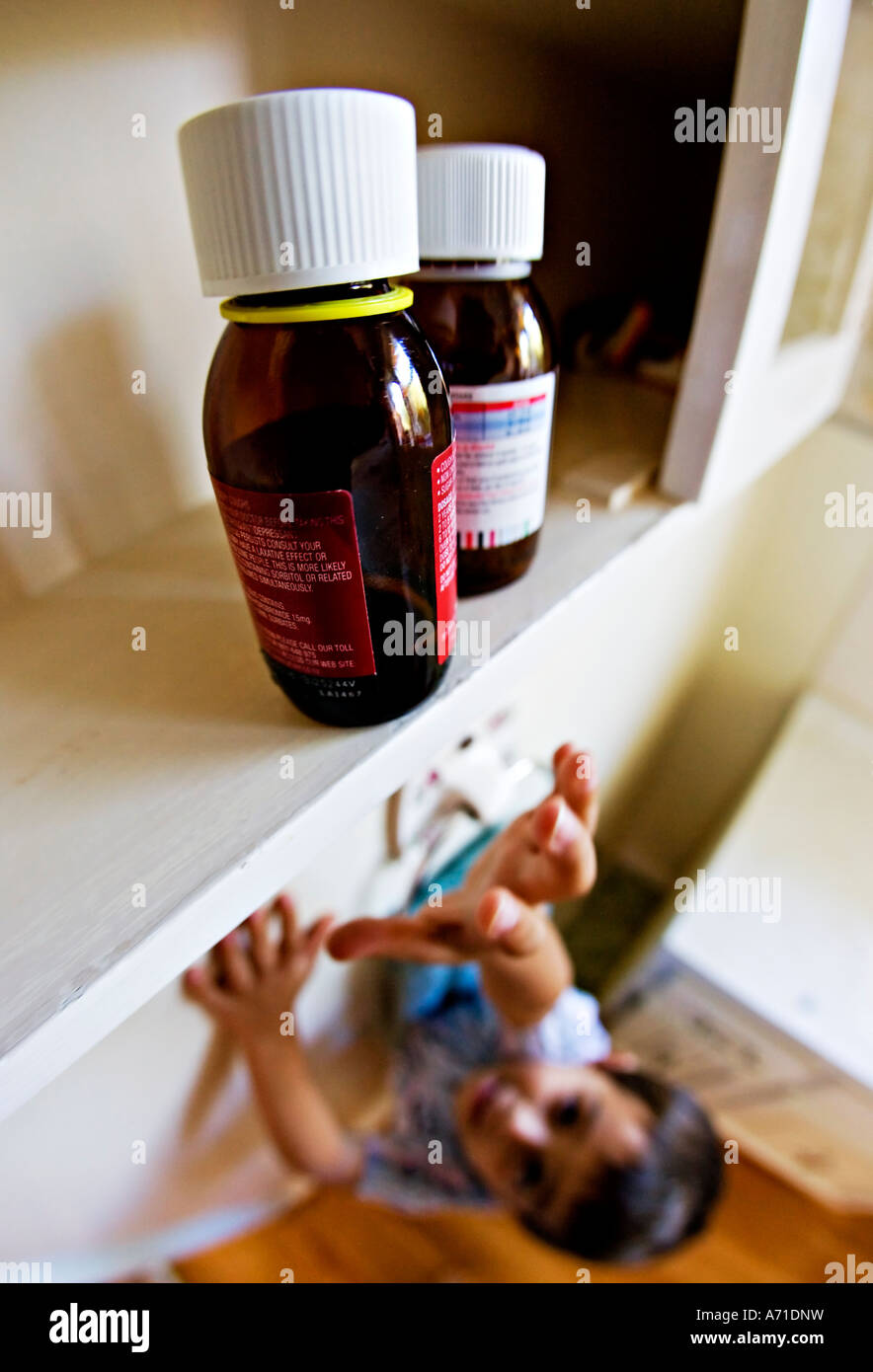 Enfant atteignant jusqu'à armoire à pharmacie dans la salle de bains Banque D'Images