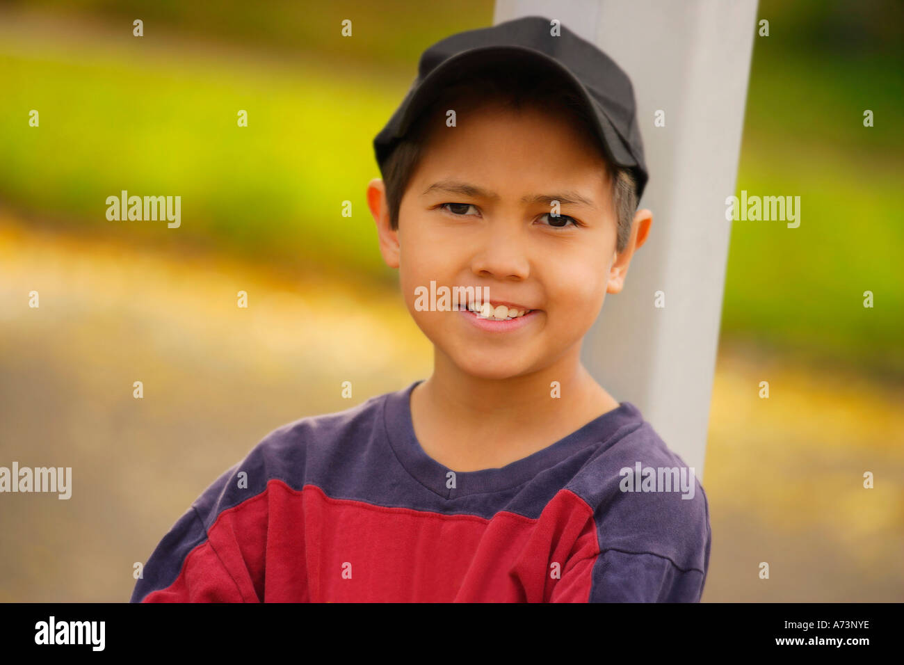Portrait d'un garçon appuyé contre un poteau Banque D'Images