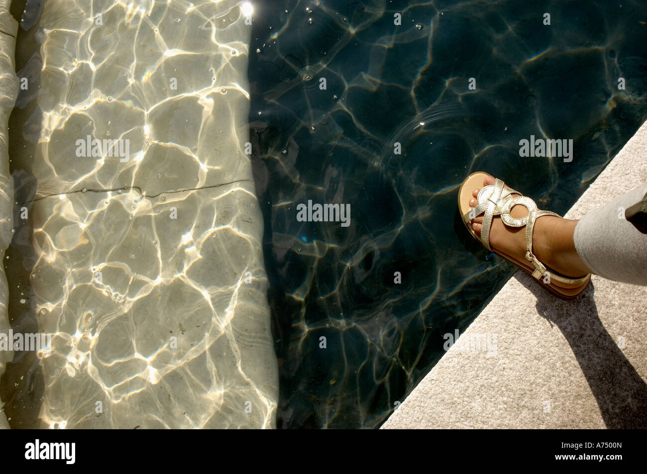 Le pied dans la sandale dorée à côté piscine Banque D'Images