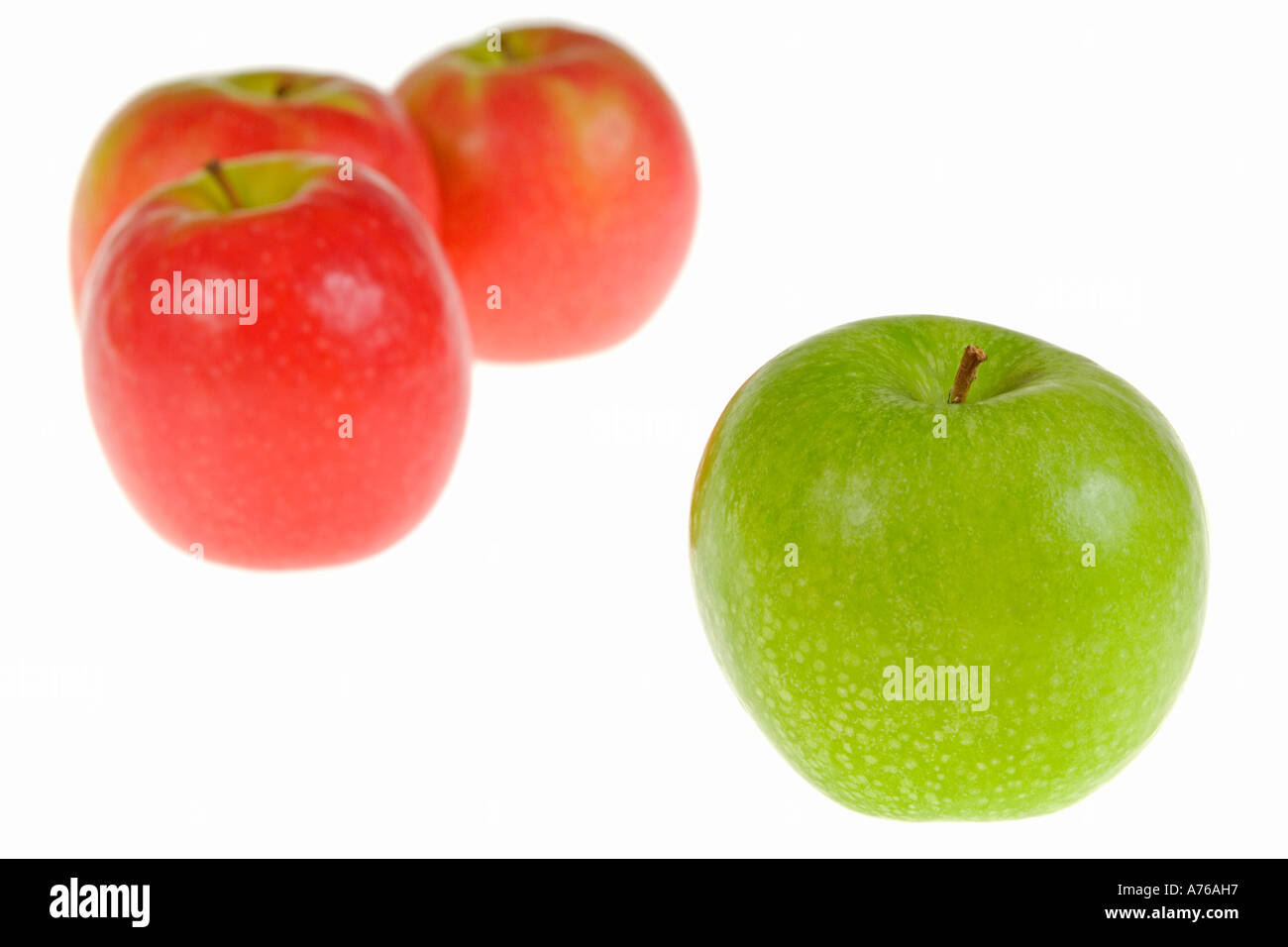 Trois pommes rouges et une seule pomme verte sur un fond blanc, pur. Banque D'Images