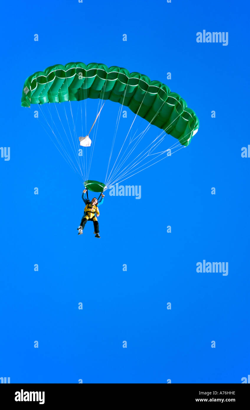 Parachutistes Buddy dans le ciel variable avec un parachute de couleur verte et un fond de ciel bleu. Banque D'Images