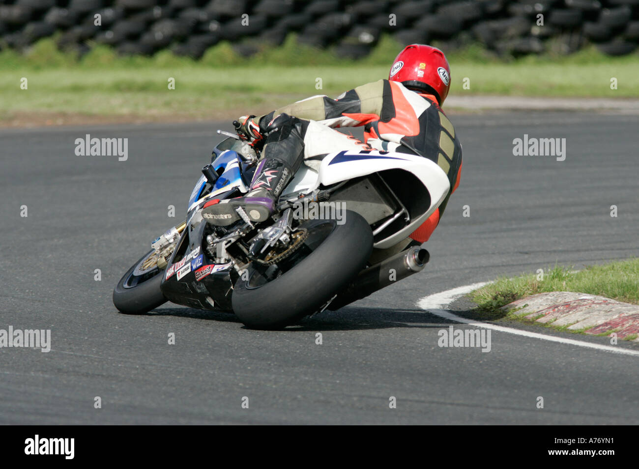 Motocycliste en cuir et casque rouge passe au coin rond vitesse lors du circuit Kirkistown trackday county down Banque D'Images