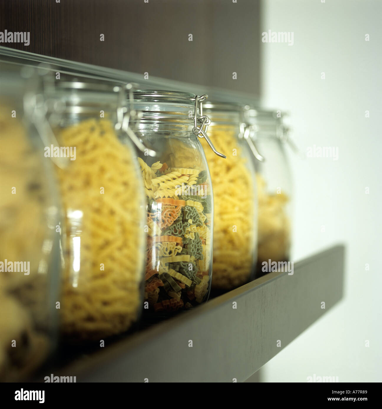 Bols de pâtes sèches multicolores sur étagère en acier brossé dans la cuisine Banque D'Images