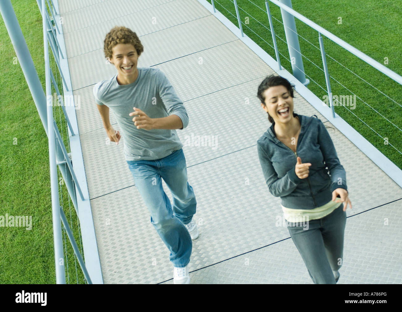 Teenage couple running on walkway, rire, high angle view Banque D'Images
