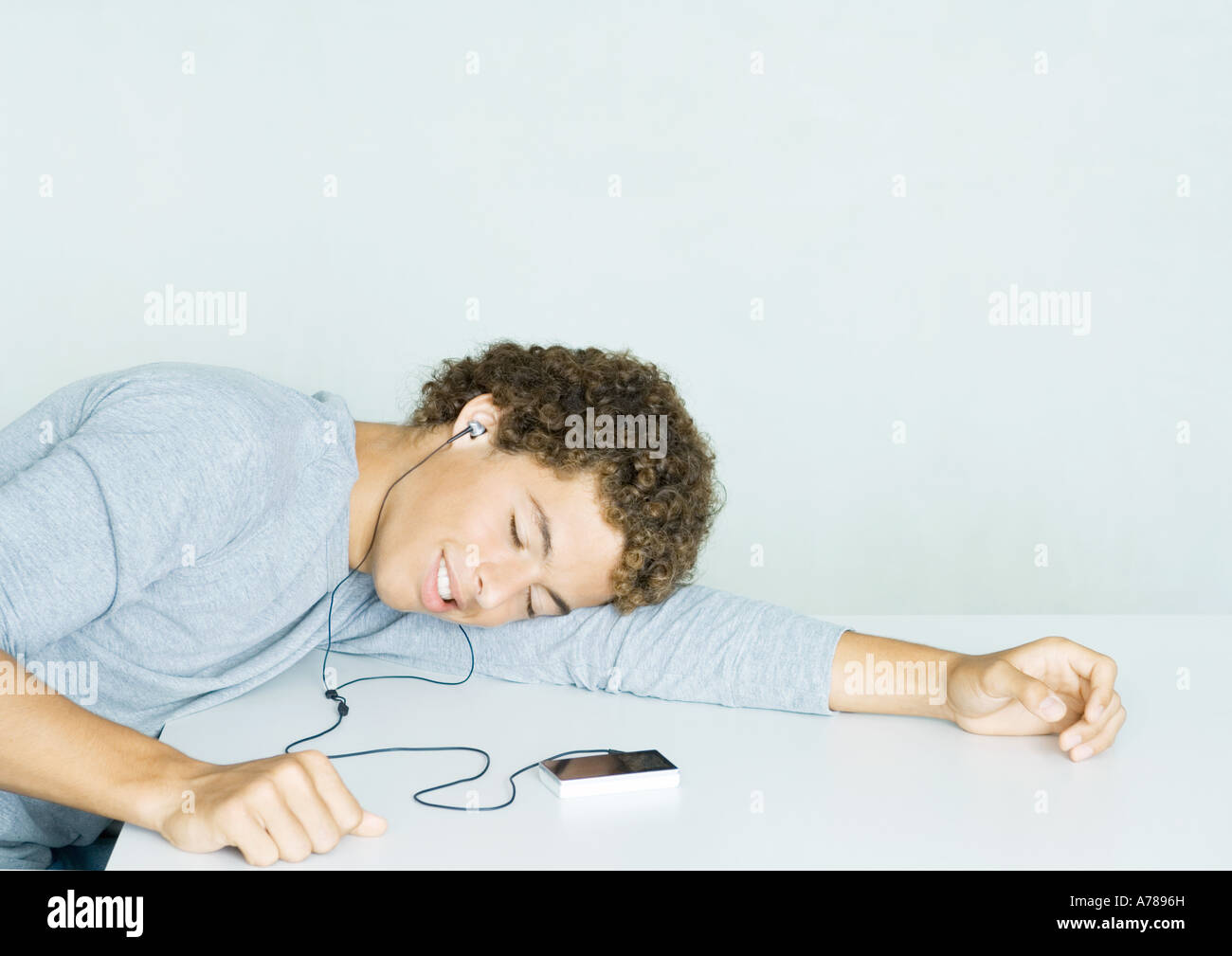 Teenage boy listening to MP3 player, tête reposant sur le bras et les yeux fermés Banque D'Images