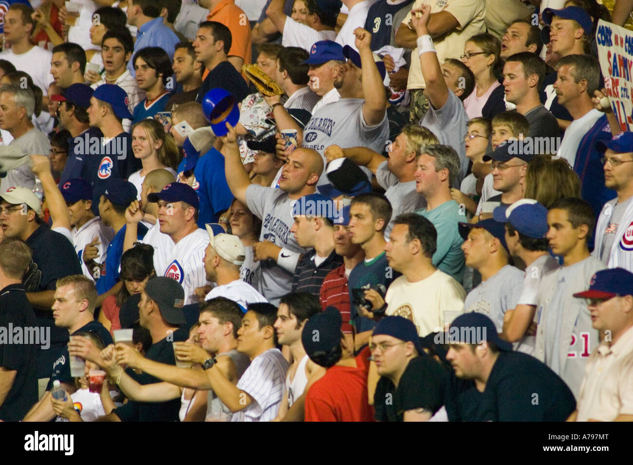 Chicago Illinois SPORTS jeu de nuit à Wrigley Field fans dans les gradins debout les bras de pompage dans l'air Banque D'Images