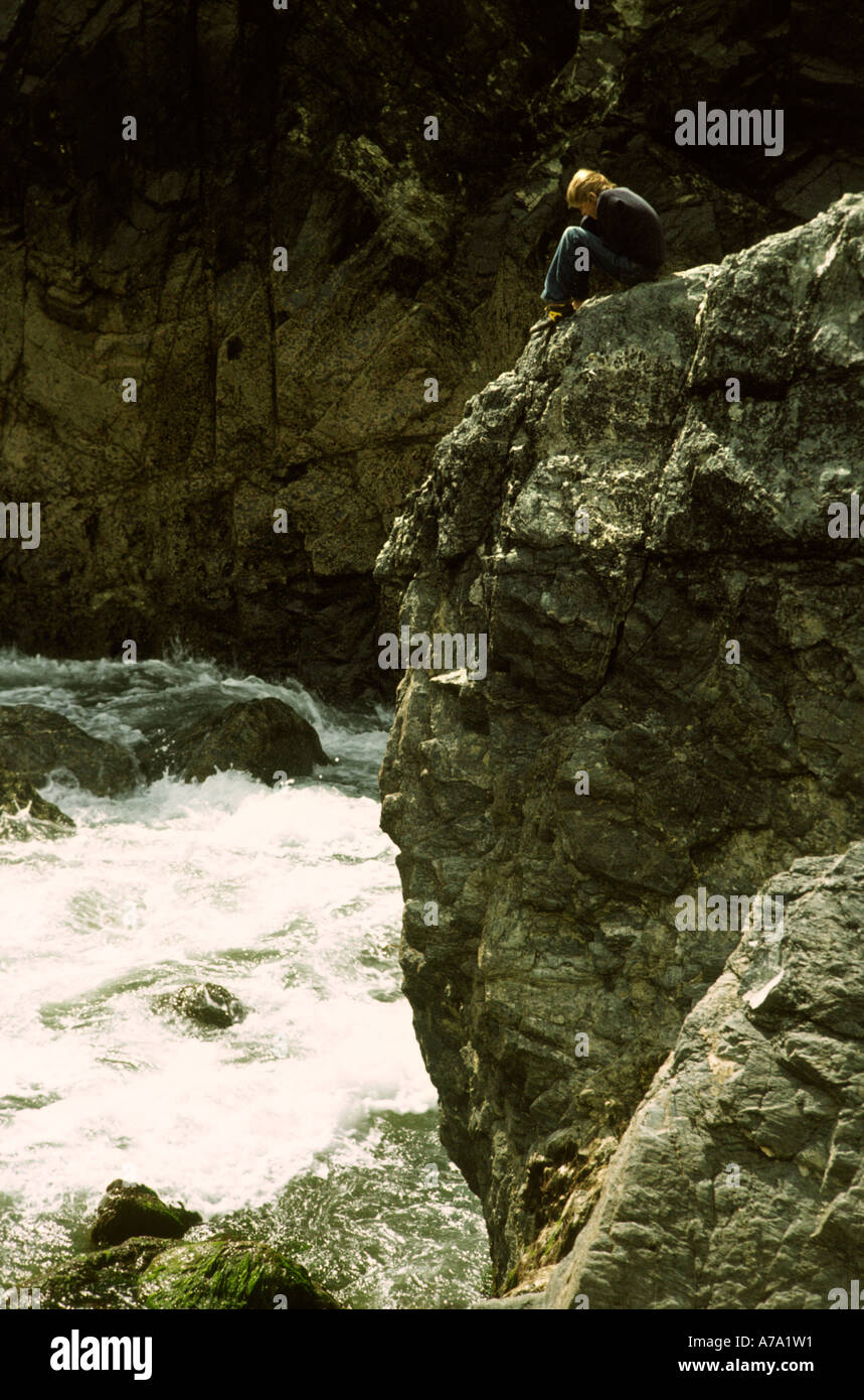 Cornwall Meneau enfant assis sur le rocher au-dessus de la mer Banque D'Images