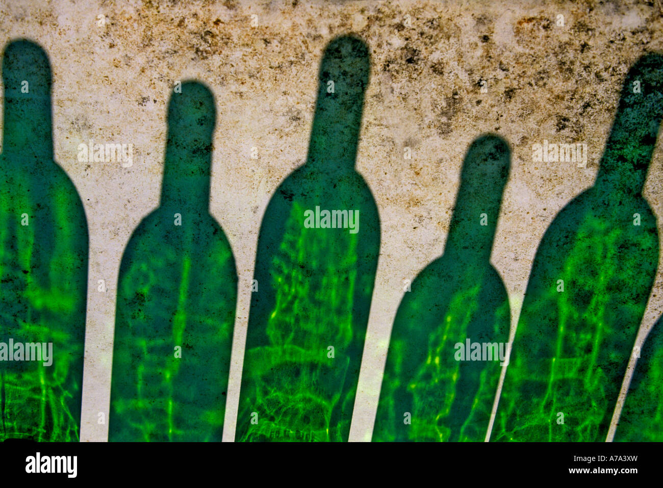 Cinq bouteilles en verre vert disposées étroitement ensemble projettent des ombres vibrantes sur une surface texturée Banque D'Images