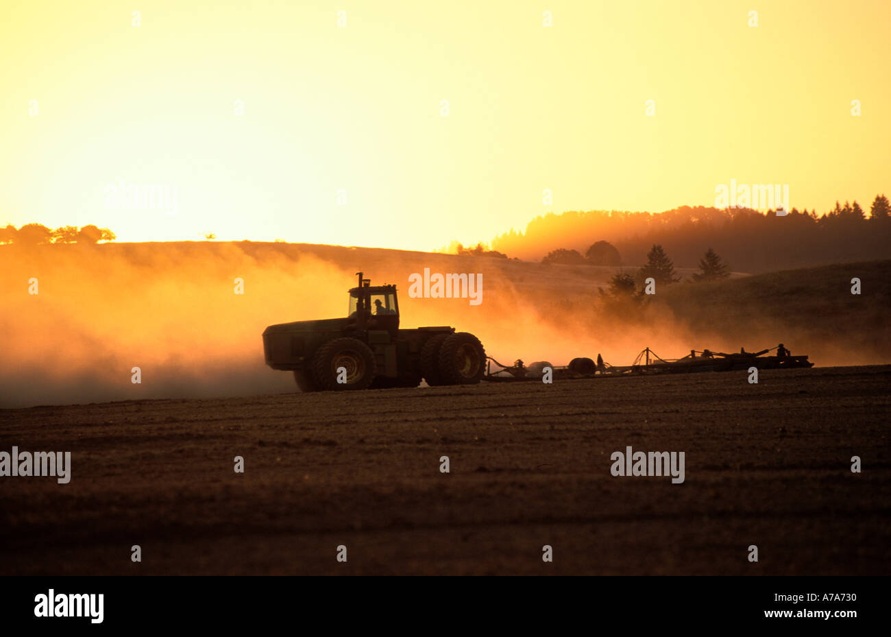 L'agriculture de l'Oregon. Tracteur de ferme avec terrain de labour au coucher du soleil. Banque D'Images