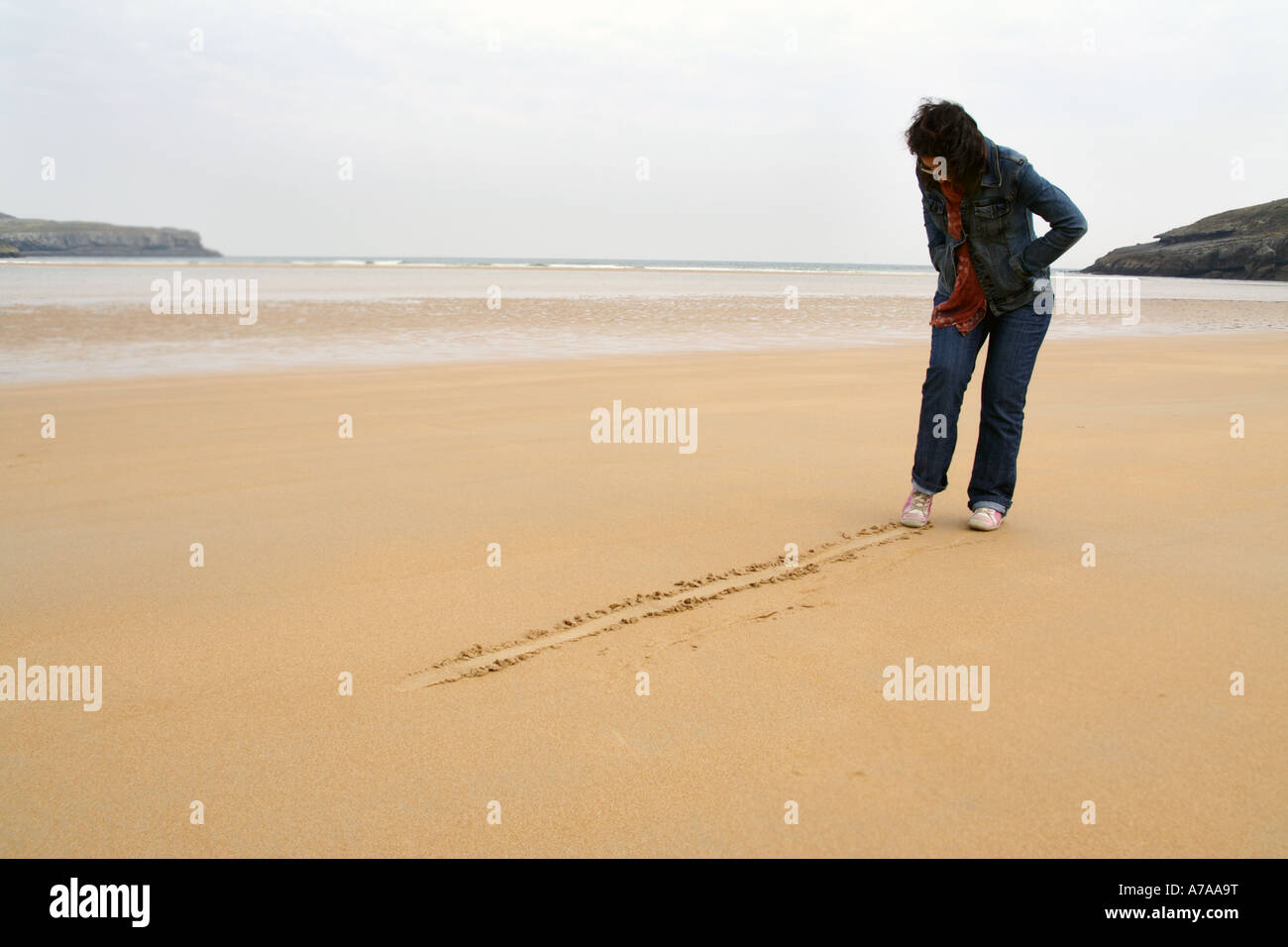 Jeune femme dessinant une ligne dans la plage Banque D'Images