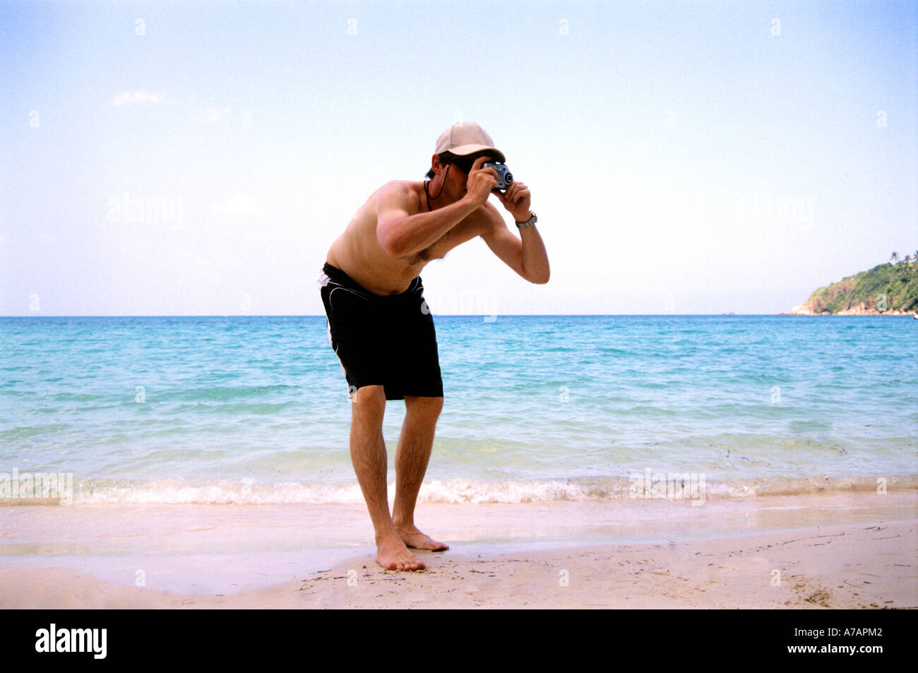 Jeune homme à l'aide d'appareil photo pour prendre des photos on tropical beach Banque D'Images