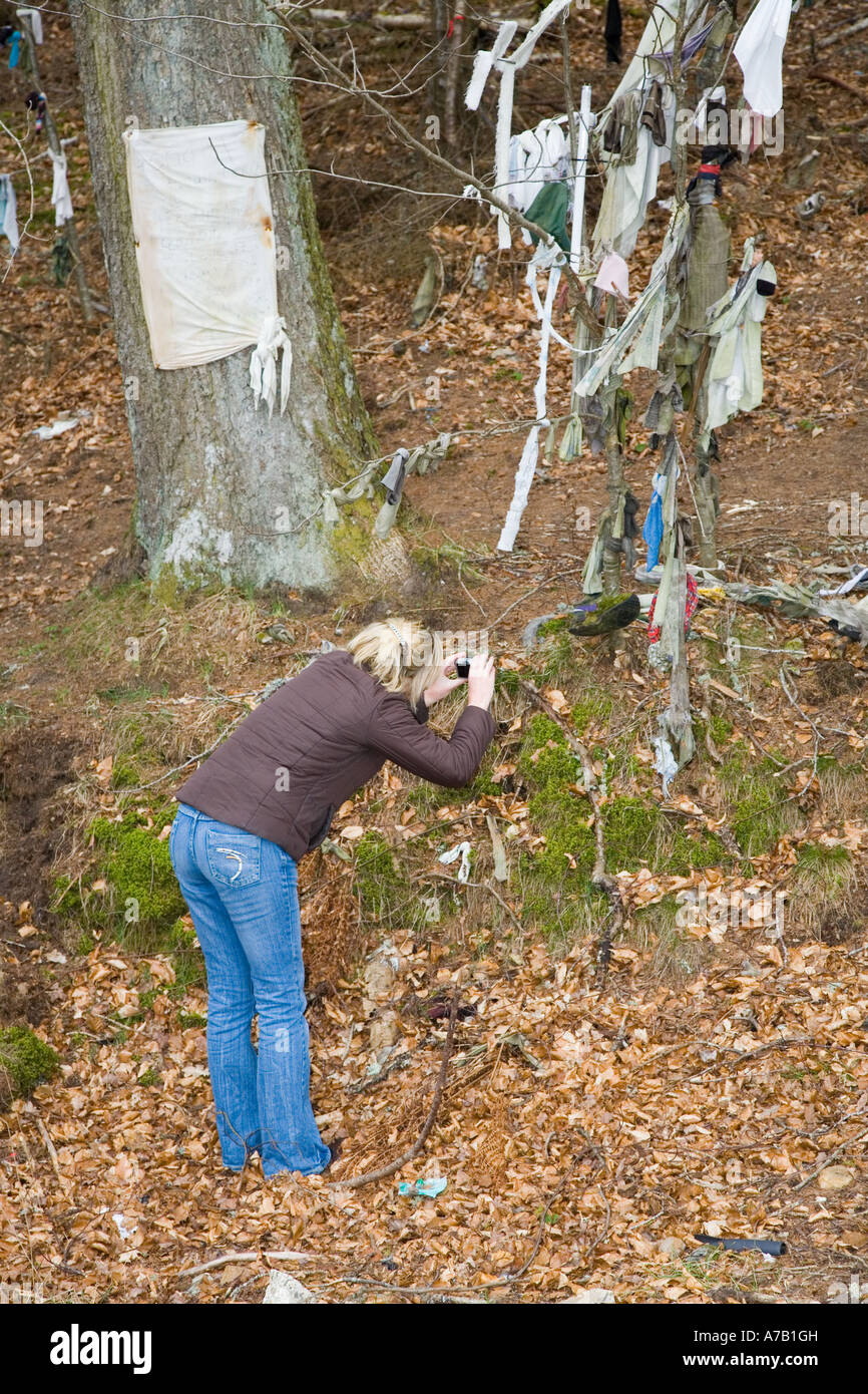 Tourisme prenant des photos à Clootie bien, des bandes de tissu ou de chiffons ont été laissés, liés aux branches de l'arbre dans un rituel de guérison.Munlochy, Royaume-Uni Banque D'Images