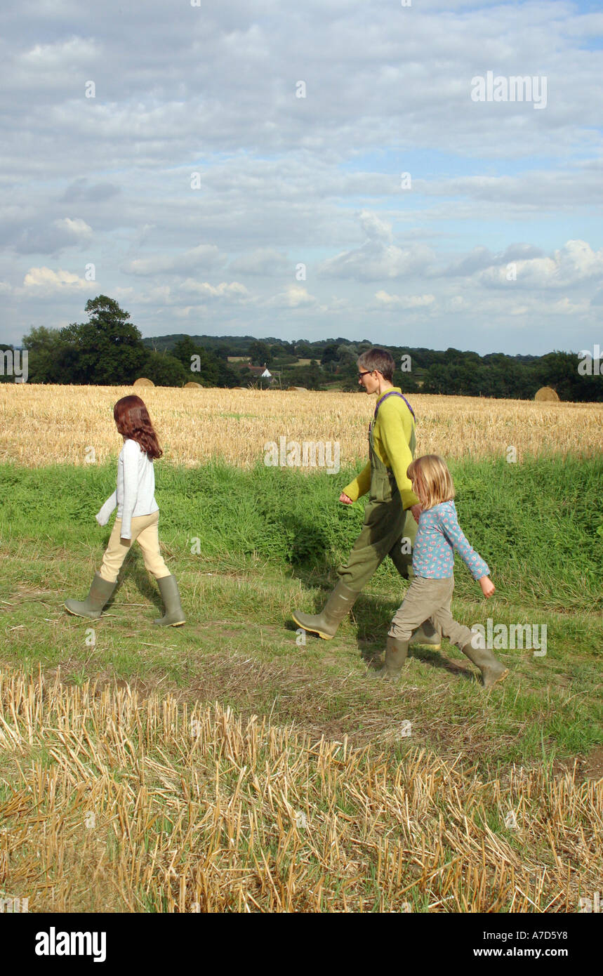 Mère marcher dans un champ avec ses deux filles dans la campagne du Sussex, Angleterre Banque D'Images