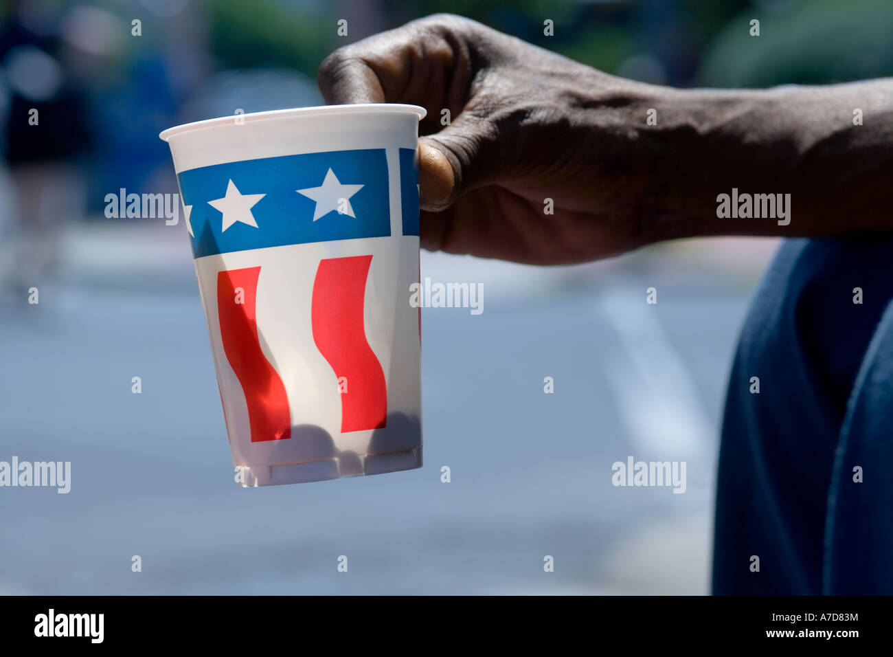 Main de mendiant, panhandler, holding out paper cup avec décor drapeau américain sur Pennsylvania Avenue, Washington DC. Banque D'Images