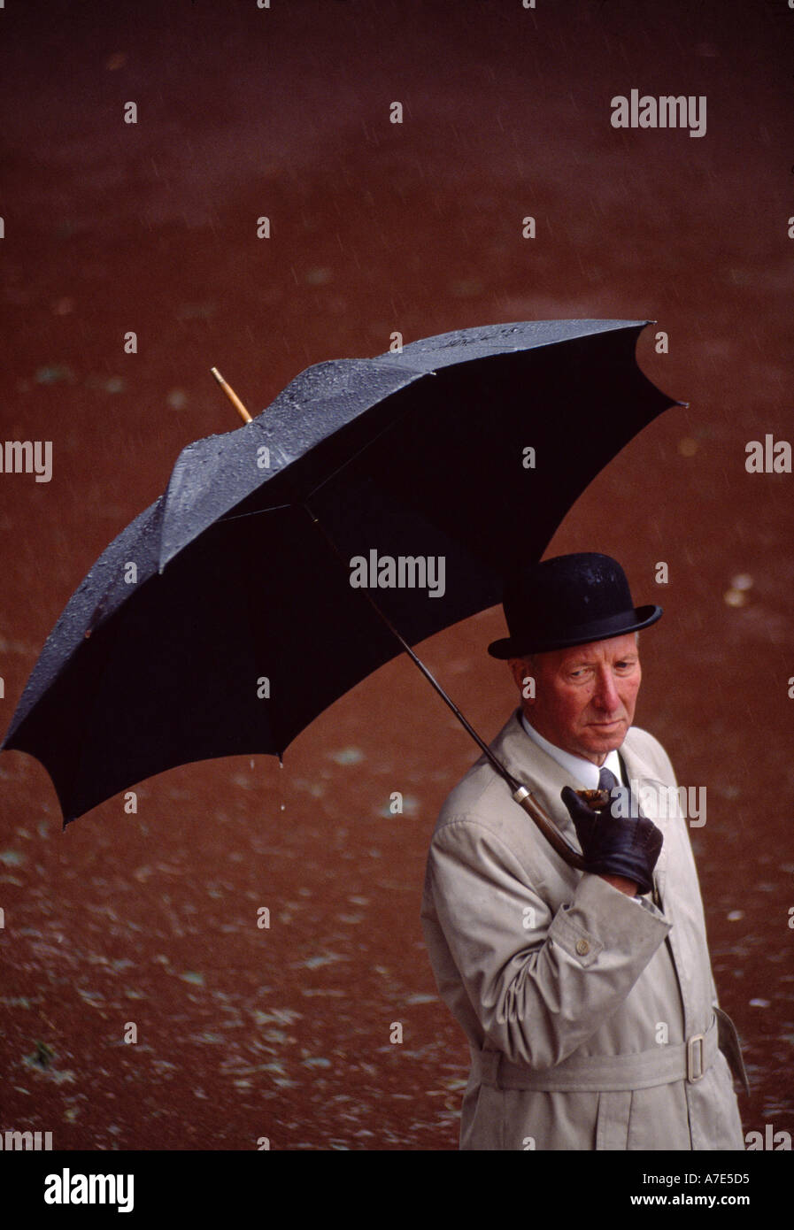 Un homme d'hébergement de la pluie sous un parapluie à la race course Ascot Berkshire en Angleterre Banque D'Images