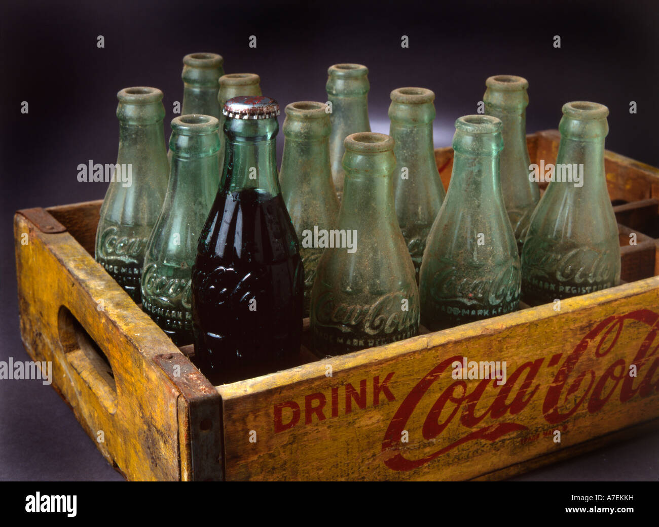 Une bouteille pleine et un groupe de bouteilles vides. Bouteilles de Coca Cola vintage en caisse en bois Banque D'Images