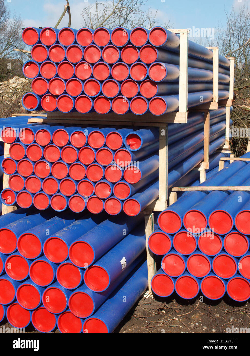 Des piles de conduites d'eau en plastique bleu équipé de butées fin rouge en attente d'utilisation dans les travaux de la rue pour le renouvellement des canalisations d'eau souterraines Essex England UK Banque D'Images