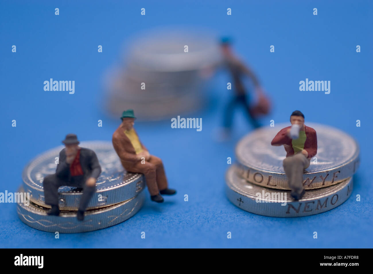 Pièces d'une livre sterling de pièce de monnaie du Royaume-Uni avec des modèles miniatures de gens assis sur les pièces Banque D'Images