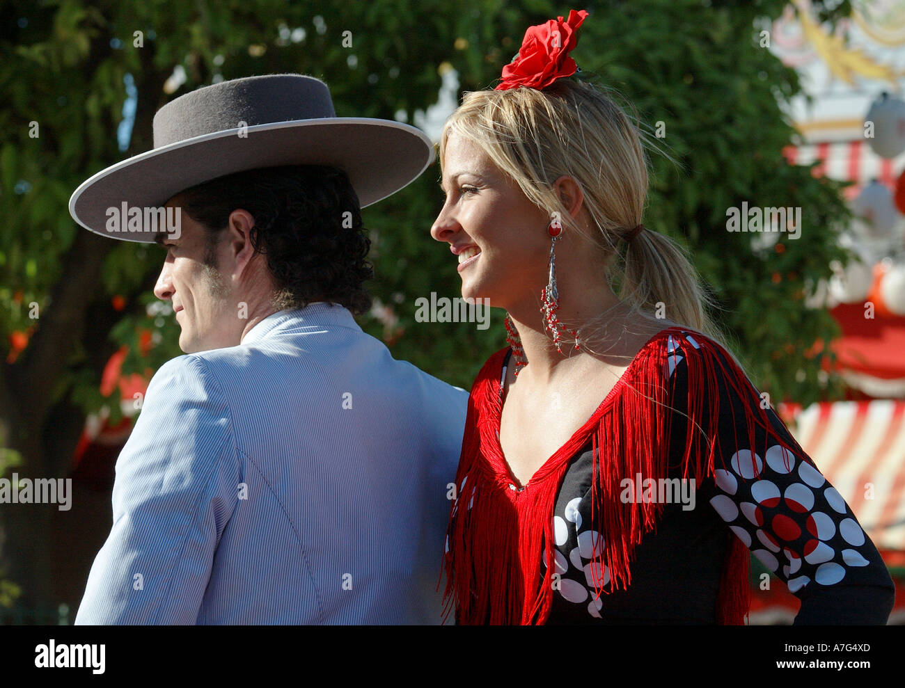 L'homme en costume traditionnel avec une fille dans une robe flamenco derrière lui à travers Séville, Espagne juste Avril Banque D'Images