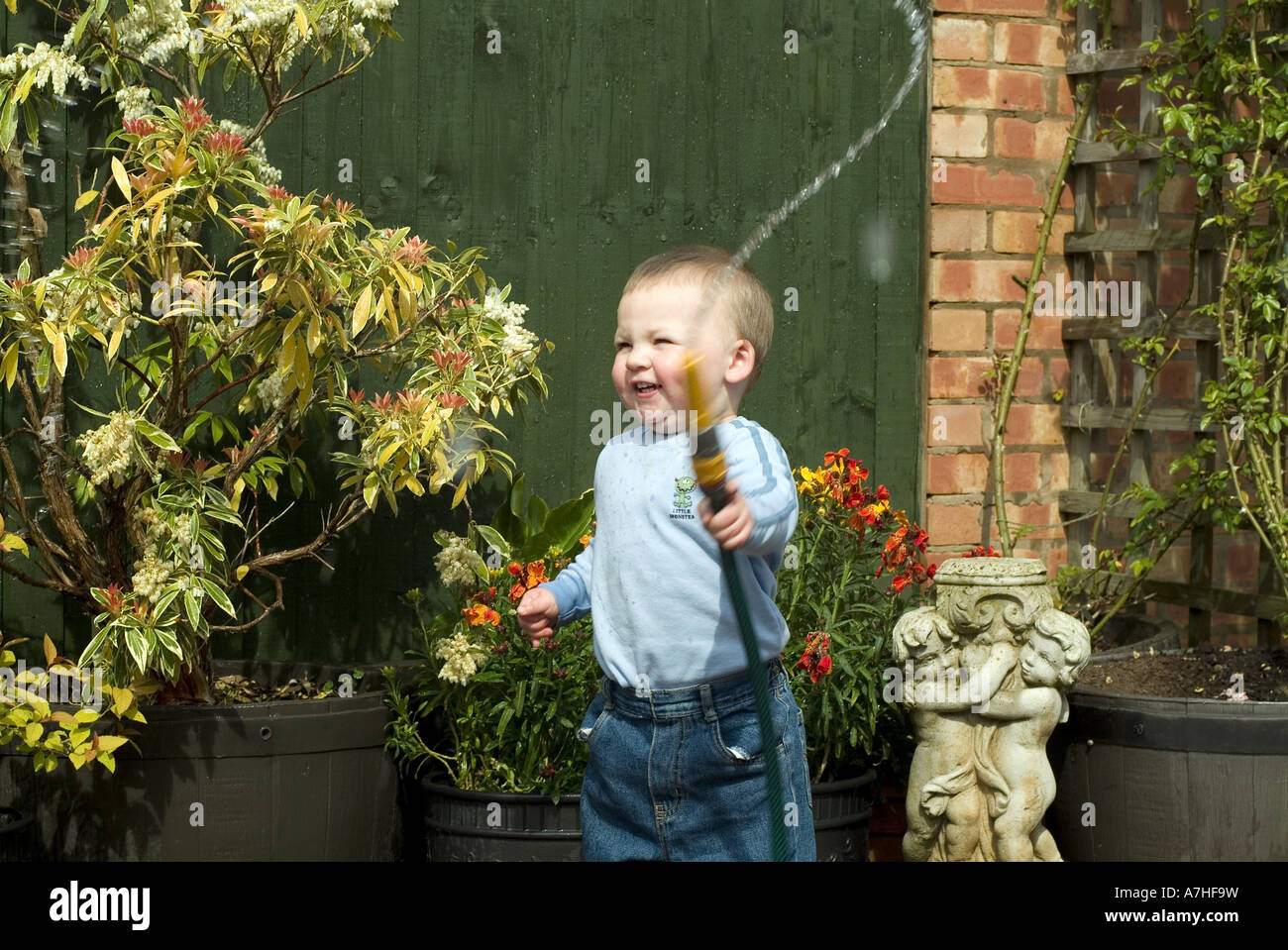 Jeune garçon jouant avec tuyau de jardin Banque D'Images