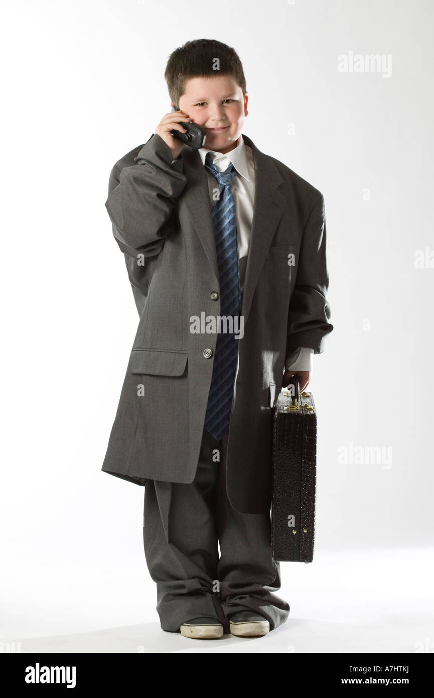 Garçon dans grandi vêtements surdimensionnés business costume et cravate  talking on cell phone tenant une serviette à studio fond blanc Photo Stock  - Alamy
