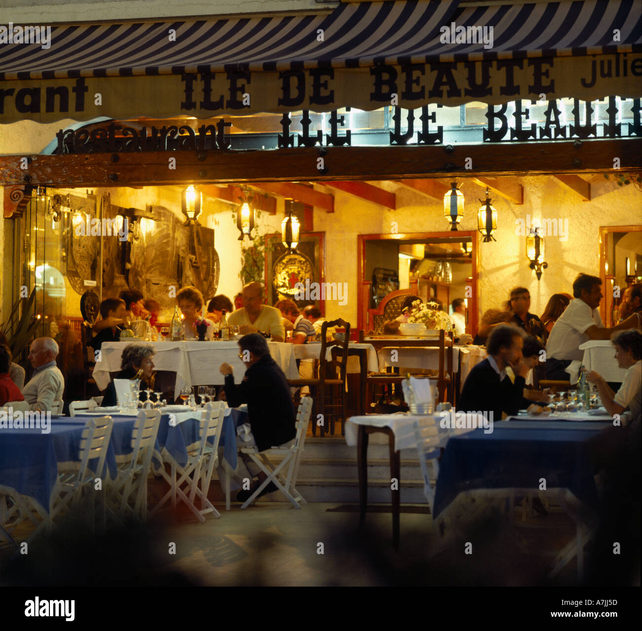 Vue de nuit à bord de l'eau du port avec les personnes et les familles manger dehors en pleine lumière restaurants à Calvi Corse Banque D'Images