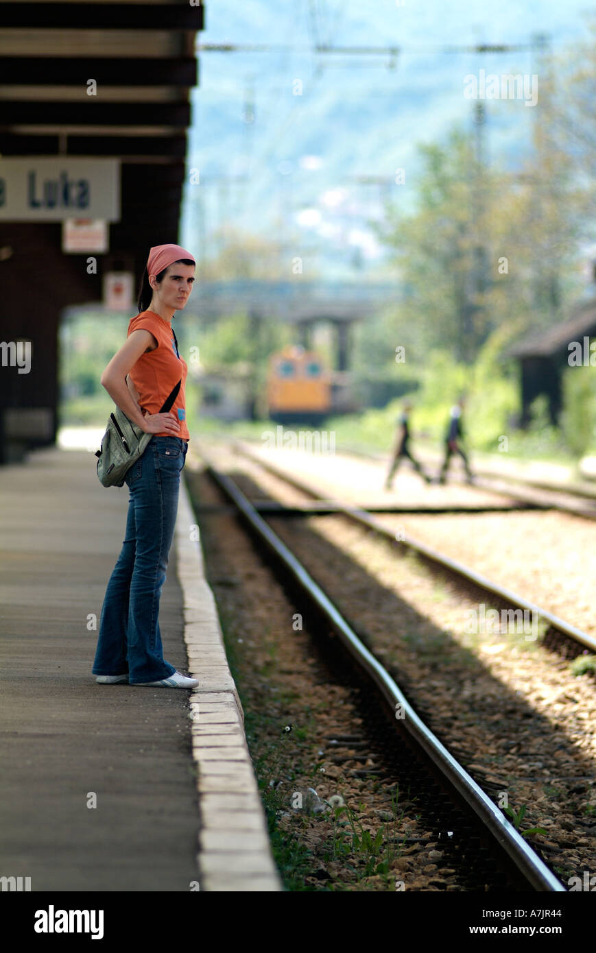 Femme Attendant sur une plate-forme du train à la recherche dans l'axe de la voie ferrée dans l'Expectative Banque D'Images