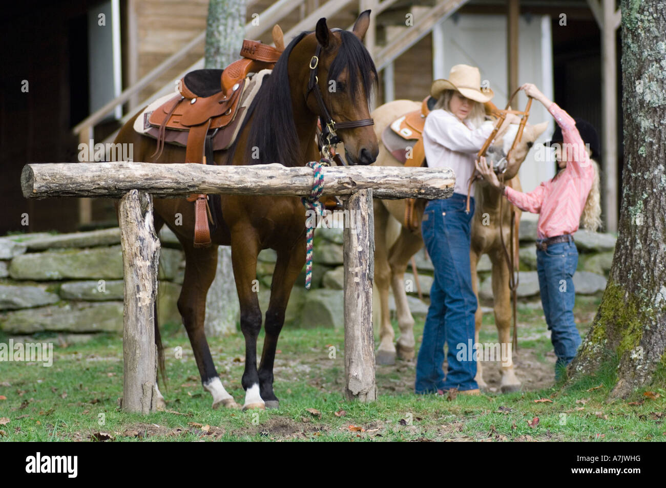 Mère et fille, lacer les chevaux pour une balade Banque D'Images