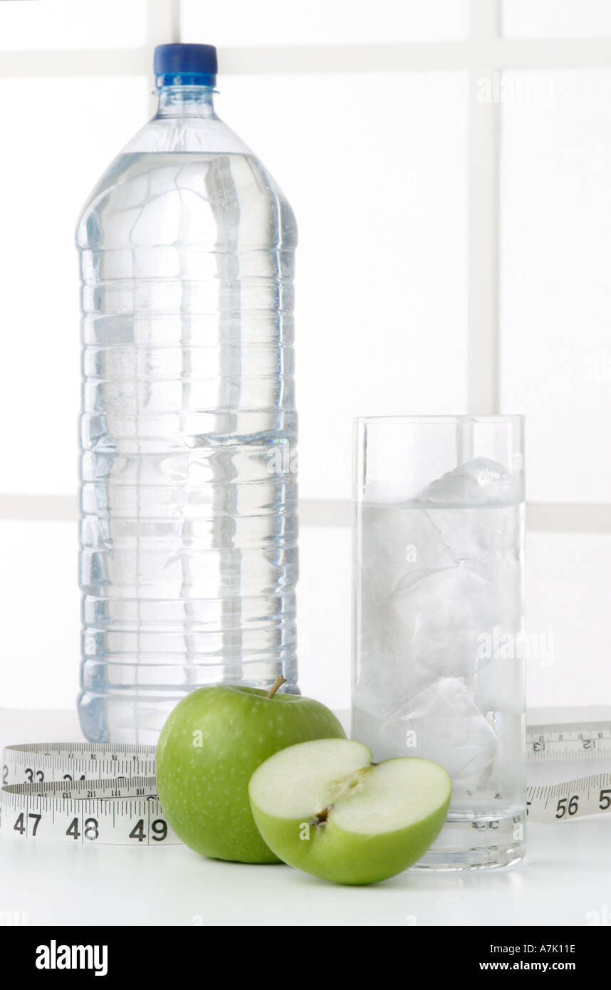 PORTRAIT D'UNE BOUTEILLE D'EAU AVEC UN VERRE D'EAU ET DEUX POMMES UN ENSEMBLE ET UNE COUPE DANS LA MOITIÉ avec un ruban à mesurer Banque D'Images
